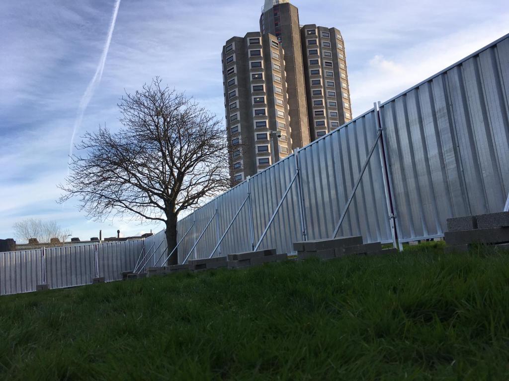 On Ground Steel Hoarding with counterweight bricks overlooking a block of flats